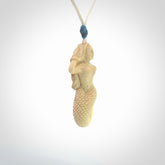 This photo shows a photo of a mermaid pendant. It is handcarved from a beautifully creamy piece of woolly mammoth tusk. It is suspended on an adjustable cord.